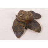 A bronze desktop trinket pot cast in the form of a walnut resting on three leaves, 4¼" long