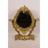 A brass framed dressing mirror with oval plate in an easel stand, 14" high, 11½" wide