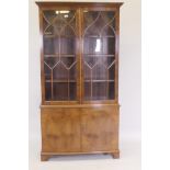 A Bevan Funnell yew wood bowfront display cabinet with astragal glazed doors over a two door