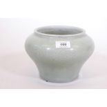 An Oriental celadon glazed bowl with decoration in low relief, inscribed to the base, 6" high
