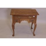 A golden oak lowboy, with three drawers and shaped apron, raised on cabriole supports with pad feet,