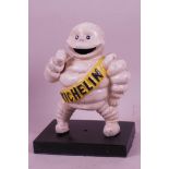 An iron figurine of a Michelin Man on a black stand, 6" high