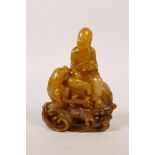 A Chinese soapstone carving of Lohan seated on a kylin, on a carved soapstone stand, with an