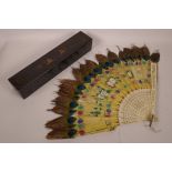 A Chinese bone and leather fan with peacock feather tips and painted floral decoration, 13" long,
