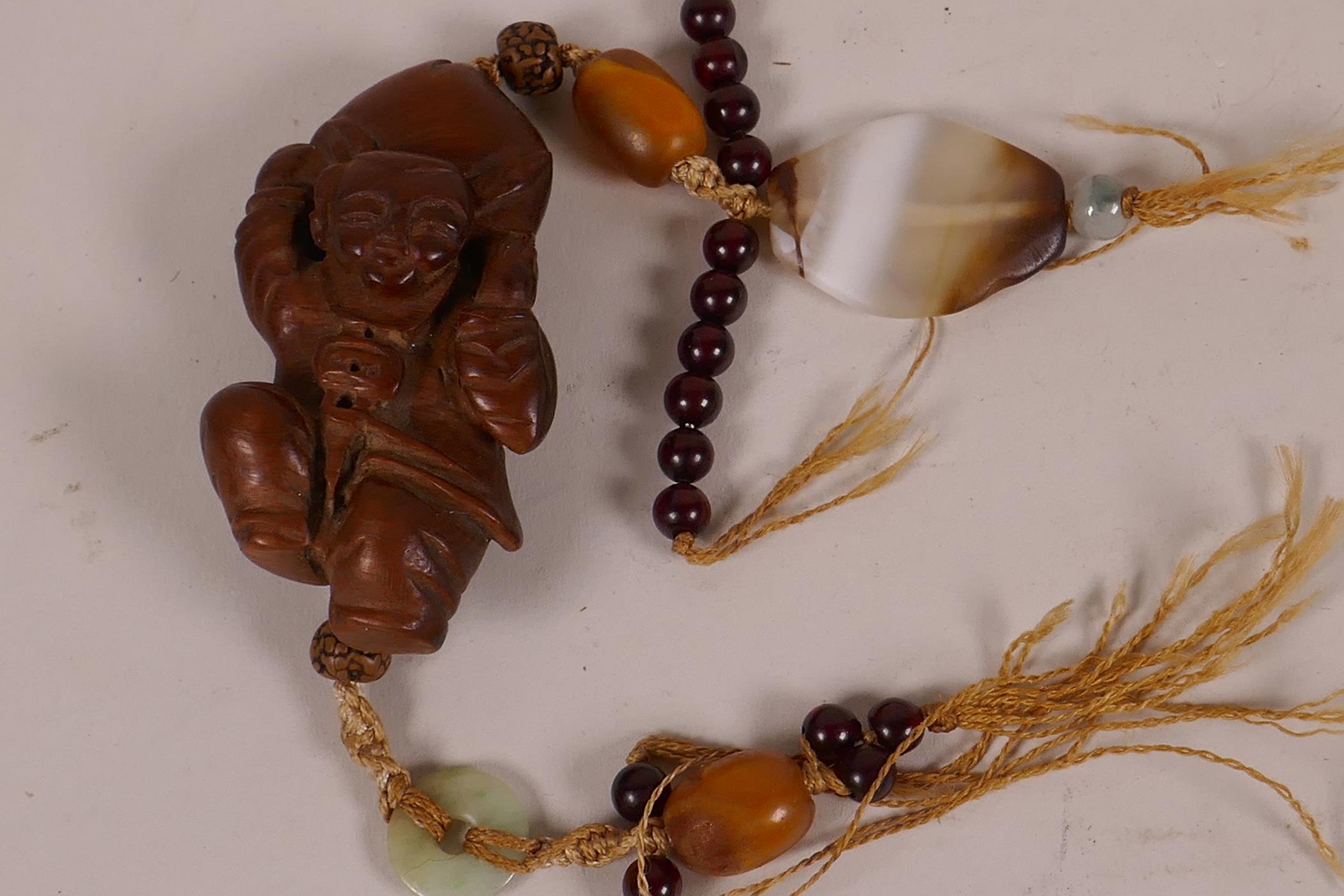 A small Chinese carved cigarwood figurine of a boy carrying a large peach, 2¼" long, strung with - Image 3 of 3