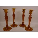 A set of four amber glass candlesticks with lozenge cut decoration, 10½" high