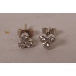 A pair of small white gold and three stone diamond stud earrings