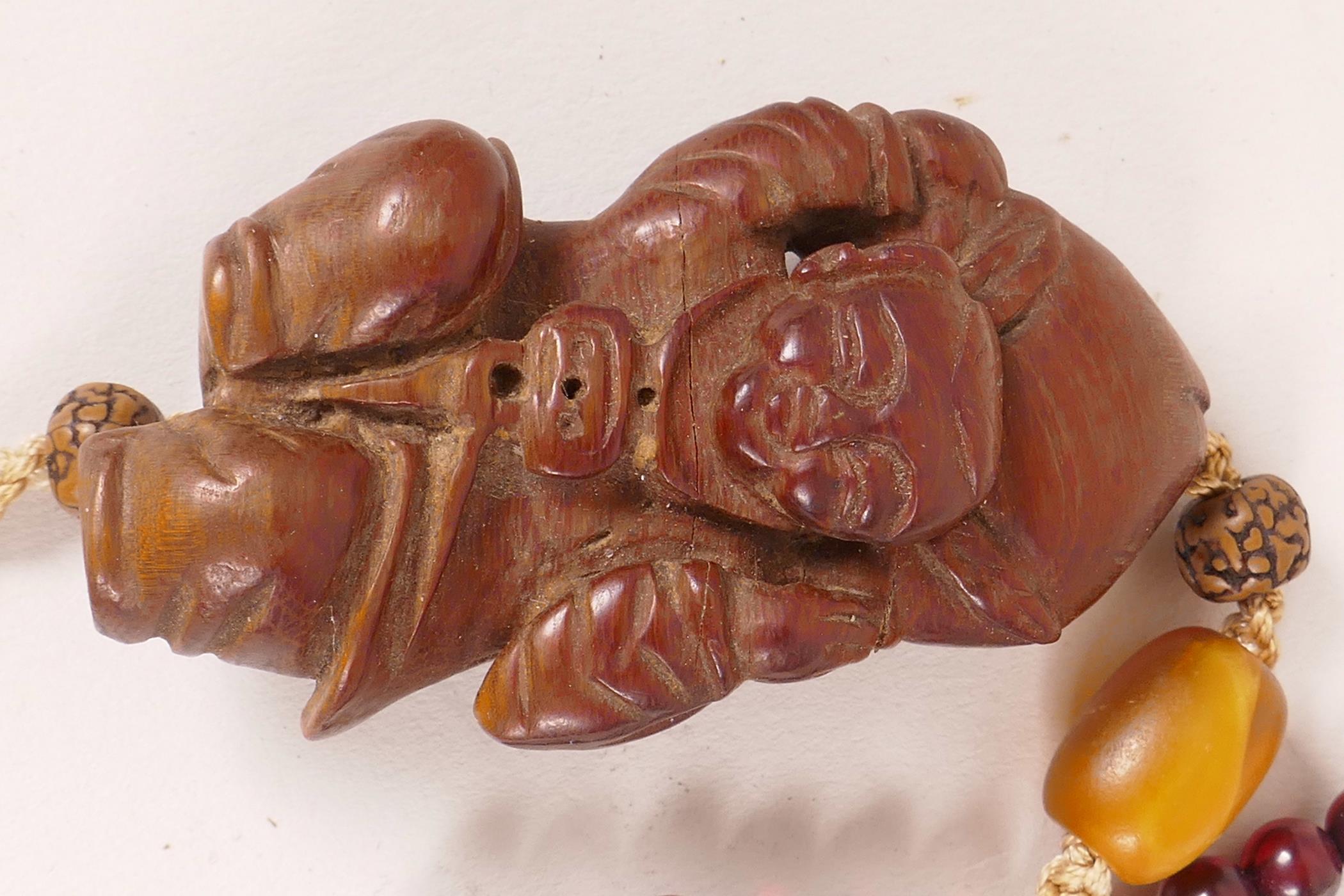 A small Chinese carved cigarwood figurine of a boy carrying a large peach, 2¼" long, strung with - Image 2 of 3