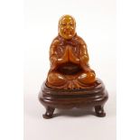 A Chinese soapstone carving of Lohan seated in meditation, on a hardwood stand, 3" high