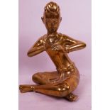 An Oriental seated brass figurine of a flautist, 9½" high