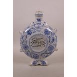 An Islamic blue and white pottery flask with four lugs, scrolling floral decoration and central