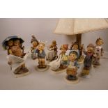 A collection of nine Goebel Hummel figurines and a Goebel Hummel table lamp