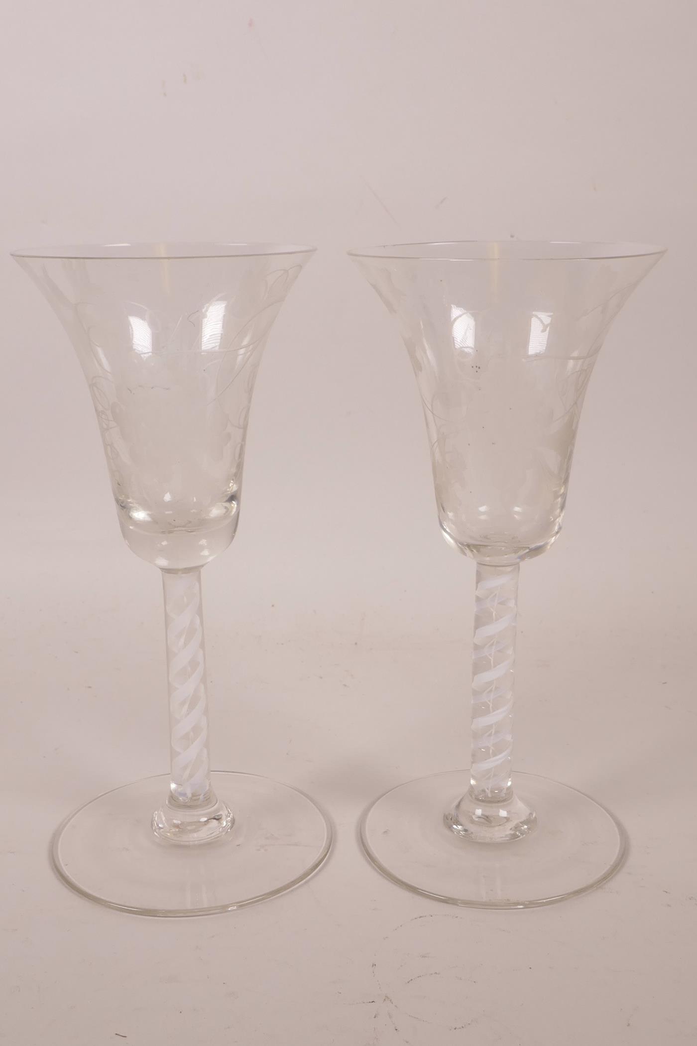 A pair of Georgian wine glasses with air twist stems and etched vine and bird decoration, 6½" high