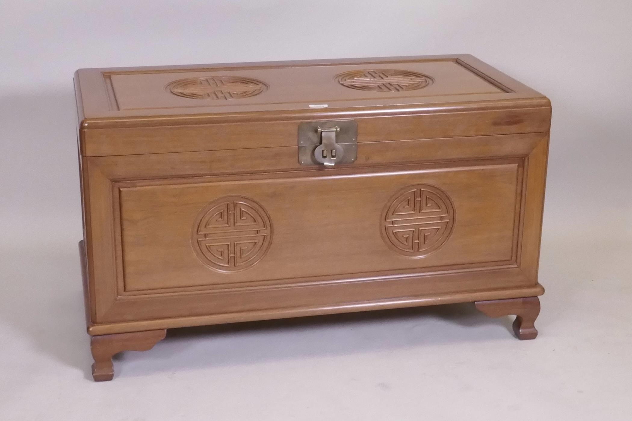 A Chinese camphorwood blanket chest with carved decoration, raised on shaped supports, late C20th,
