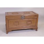 A Chinese camphorwood blanket chest with carved decoration, raised on shaped supports, late C20th,