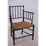 An early C19th rush seated open armchair, raised on turned supports, traces of original black and