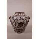 A Chinese red and white porcelain vase with two mask handles and scrolling lotus flower