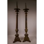 A pair of brass pricket candlesticks on Corinthian columns and triform bases, 35" high