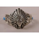 A 925 silver bangle decorated with a Native American and associated motifs, set with two turquoise