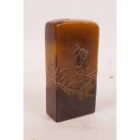 A Chinese bi-colour soapstone seal with carved decoration of figures in a landscape, 3" high