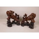 A pair of Chinese hand carved figurines of tigers with glass eyes and bone teeth, on carved wood