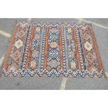 An Eastern tribal hand made Kilim rug with bands of geometric patterns in brown, blue, black and