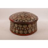 An Indian painted wood cylinder box decorated all over with white metal repoussé floral plaques, 10"
