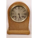 An inlaid oak cased dome top mantel clock, with silvered dial and Roman numerals, the movement