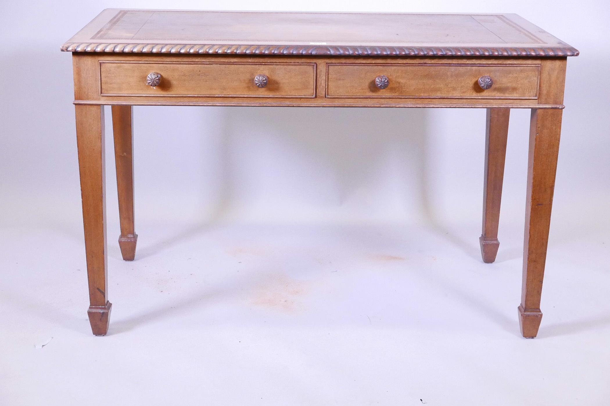 A mahogany two drawer writing table, with gadrooned edge and inset blind leather tooled top,