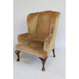 A Georgian wing back armchair on mahogany cabriole front supports (for reupholstery)