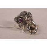 A white metal ring in the form of an elephant's head set with marcasite, ruby and emeralds,