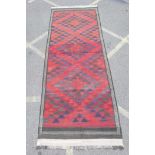 An antique Afghan Kilim rug with geometric design on a red field, 148" x 55"