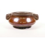 A Chinese patinated bronze censer with two ram's mask handles, impressed 16 character mark to