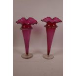 A pair of tall C19th cranberry glass vases on clear glass feet, 12" high