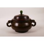 A Chinese bronze censer with two elephant mask handles, with a turned hardwood cover and jade