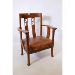 An Arts and Crafts oak bow shaped low armchair, with pierced splat back, and studded leather seat,