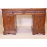 An oak six drawer kneehole desk with inset gilt tooled leather top, and carved linenfold