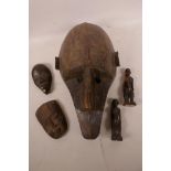 A large African carved wood tribal mask, 15" long, together with two small masks and two figurines