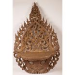 A Burmese carved wood shelf bracket carved with dragons and a fiery deity, 27" high, 17½" wide