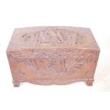 An Oriental camphorwood chest with carved dome top, on a shaped base and bracket feet, and carved
