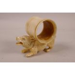 A novel carved bone napkin ring carried by a dog, 3½" long