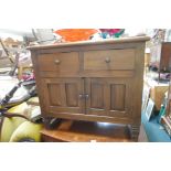 A Continental hardwood side cabinet with two drawers over two fielded panel doors on sleigh