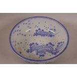 An Oriental blue and white porcelain bowl decorated with flowers and swirling symbols, 10" diameter