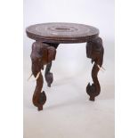 An Anglo-Indian occasional table with carved top, raised on three elephant mask supports, 25"