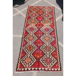 An antique Afghan Kilim rug decorated with a geometric design on a red field, 56" x 124"
