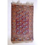 An antique Turkmeni wool rug with a Bokhara design on a tomato field, 33" x 56"