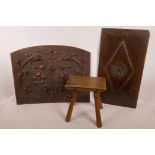 An early country made four legged elm stool, together with two carved wood panels