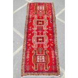 A Persian wool runner with a unique geometric medallion design on a rich red field, 52" x 126"