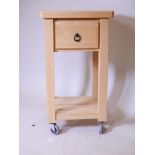 A beechwood single drawer kitchen table with undertier and braked castors, 19½" x 19½" x 37"