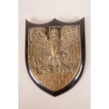 A heavy cast gunmetal wall plaque in the form of an eagle perched on a battlement, mounted on a